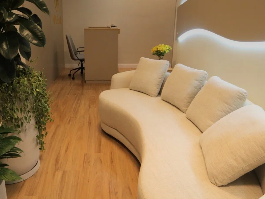 Sala de espera da clínica, com sofá curvo e plantas